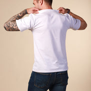 Man wearing a white t-shirt and dark jeans against a beige background