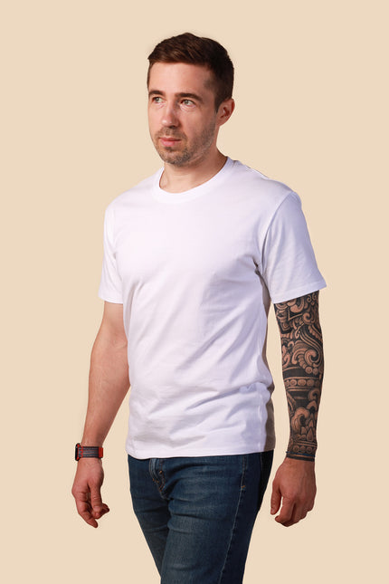 Man wearing a plain white t-shirt and dark jeans on a beige background