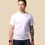 Man wearing a plain white t-shirt and dark jeans against a beige background