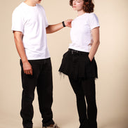 Two people wearing white t-shirts and black pants against a beige background