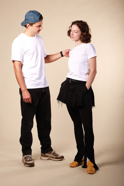 Two people wearing white t-shirts and black pants against a beige background