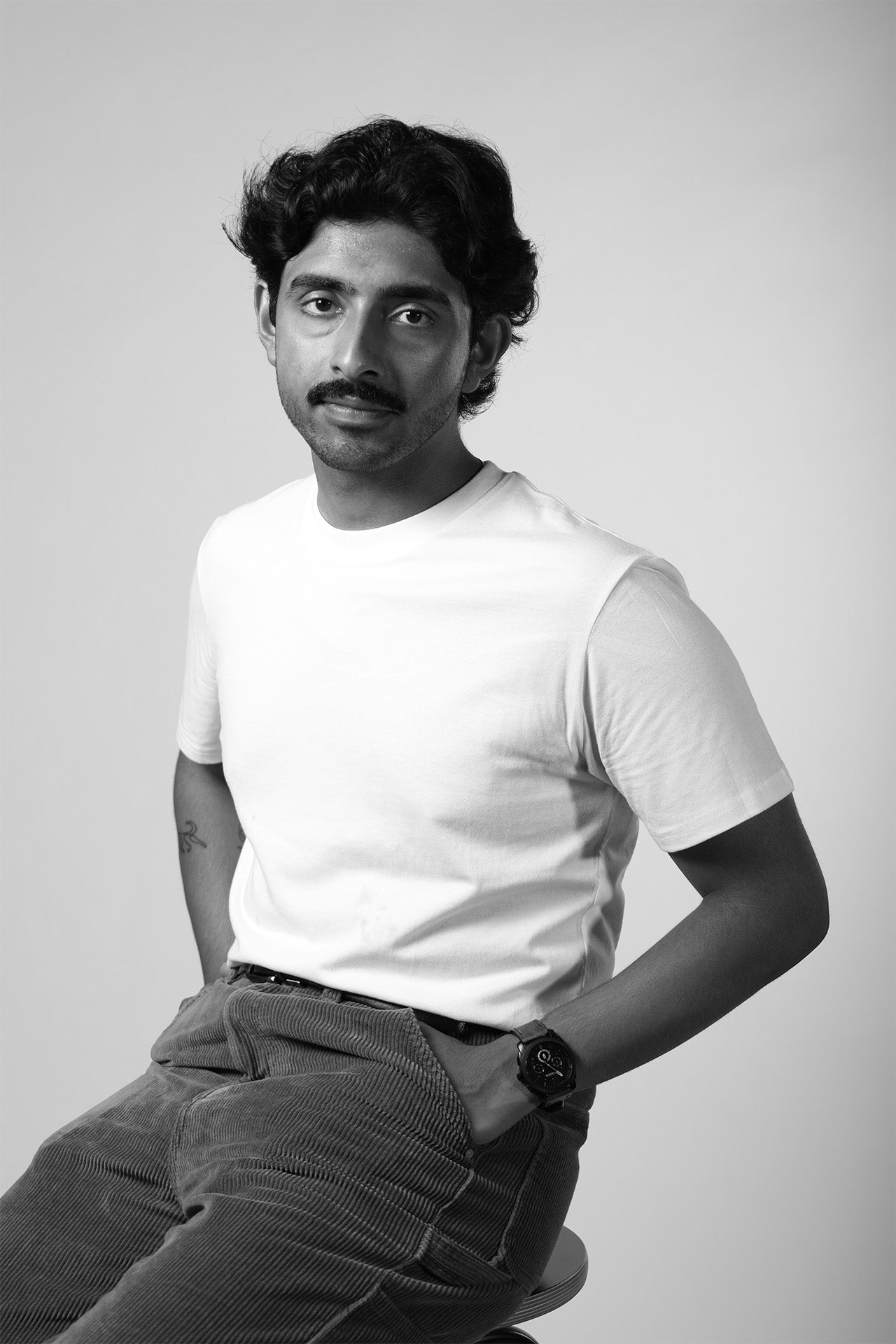 Black and white portrait of a person wearing a white t-shirt and dark pants.