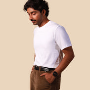 Man wearing a white t-shirt and brown pants against a beige background