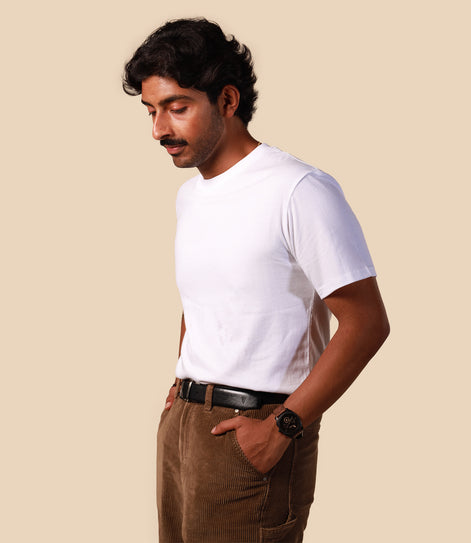 Man wearing a white t-shirt and brown pants against a beige background