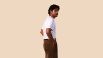 Man wearing a white t-shirt and brown pants against a beige background
