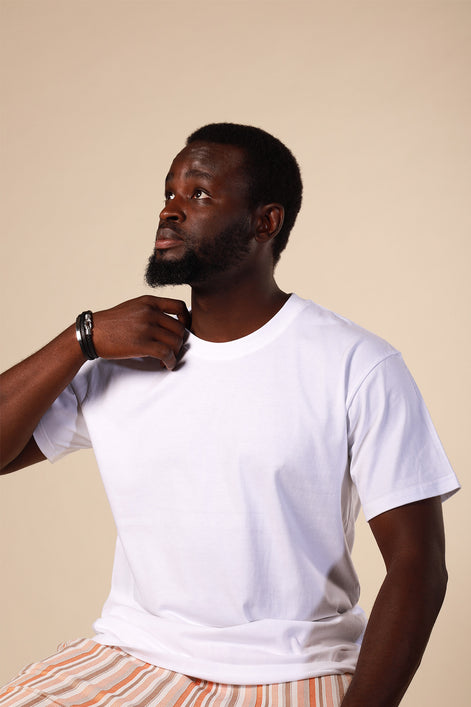 Man wearing a white t-shirt and striped pants against a beige background