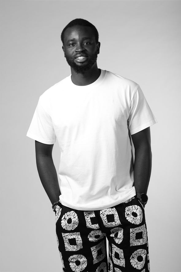 Man wearing a white t-shirt and black shorts with geometric pattern on a gray background