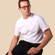 Man wearing a white t-shirt and black pants against a beige background