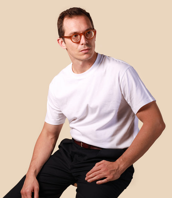 Man wearing a white t-shirt and black pants against a beige background