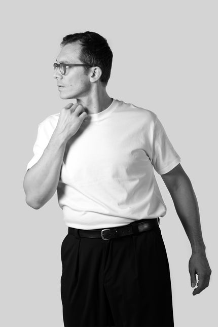 Man wearing a white t-shirt and black pants on a plain background