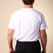 Man wearing a white t-shirt and black pants against a beige background