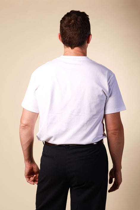 Man wearing a white t-shirt and black pants against a beige background
