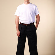 Man wearing a white t-shirt, black pants, and red shoes on a beige background