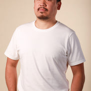 Man wearing a white t-shirt and brown cap against a beige background