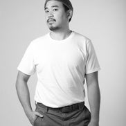 Black and white photo of a person wearing a plain t-shirt and pants on a light gray background