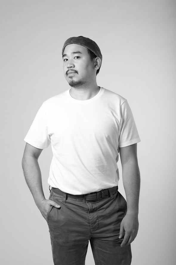 Black and white photo of a person wearing a plain t-shirt and pants on a light gray background