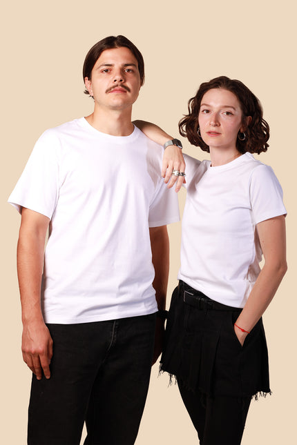 Two people wearing white t-shirts and black pants against a beige background